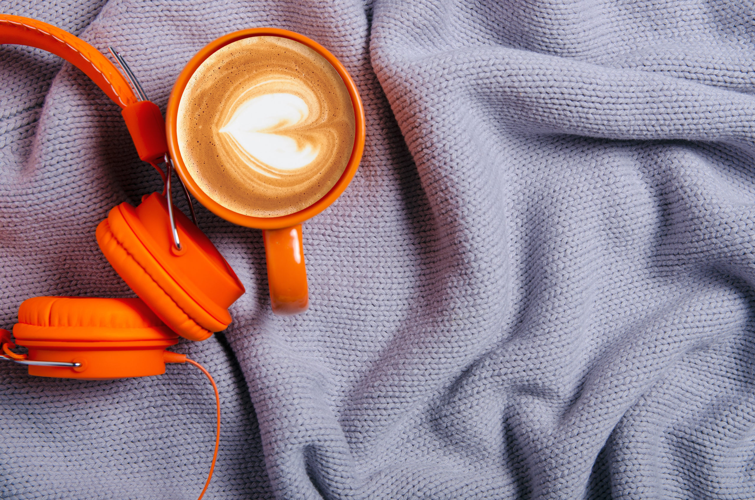 Cup,Of,Coffee,,Orange,Headphones,And,Blue,,Gray,Knitted,Sweater,