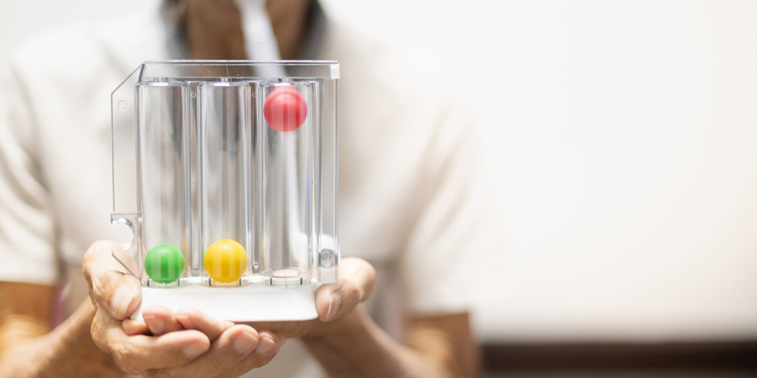 The old patient hand holding the Tri-ball incentive spirometry is medical equipment for post operation. The equipment for Lungs function testing and Pulmonary test.
