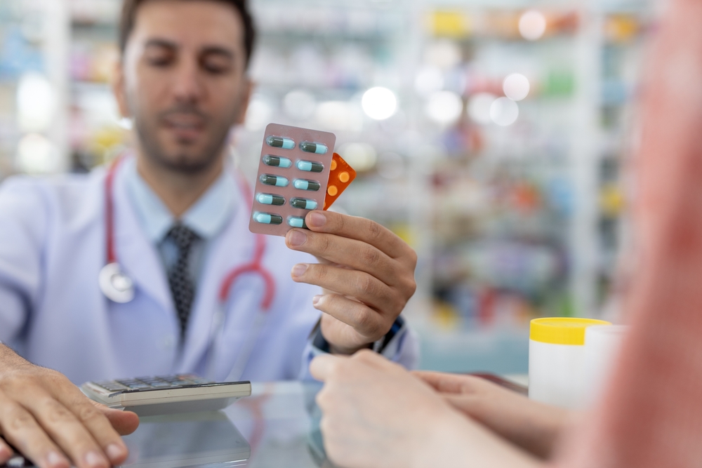 Man,Pharmacist,Holding,Medicine,Capsule,Blister,Pack,At,Counter,Dispensing