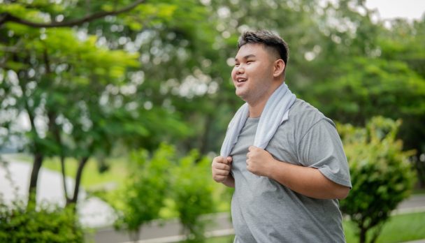 Asian plus-size man exercises outdoors in the garden to lose weight.
