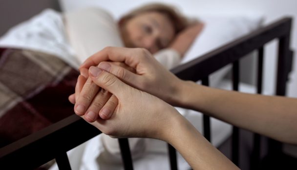 Daughter,Supporting,Her,Terminally,Ill,Mother,Lying,On,Hospital,Bed,
