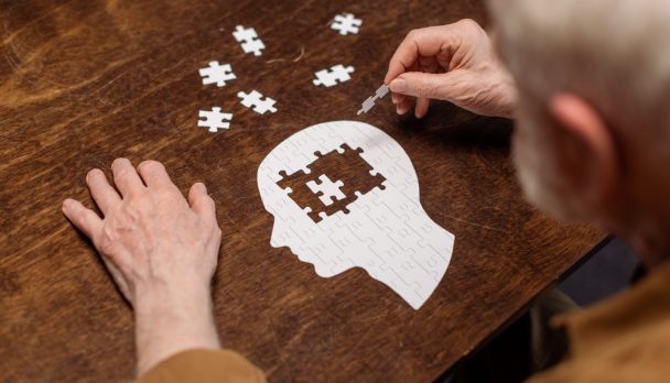 High,Angle,View,Of,Senior,Man,Collecting,Jigsaw,Puzzle,As