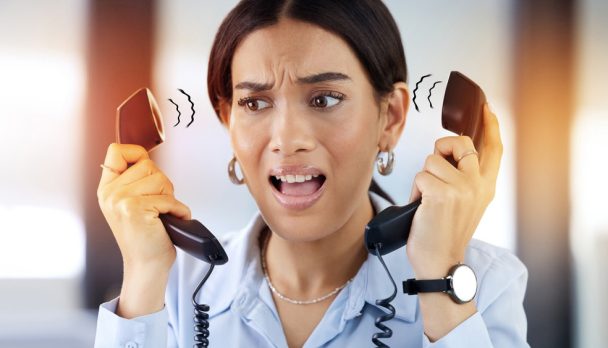 Telephone, phone call and stress of receptionist in office with anxiety, customer service or confused. Landline, overlay and secretary tension in communication for pressure, scared or problem at work